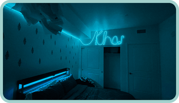 Blue neon sign lighting up a cozy bedroom at night.