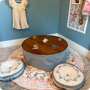 Cozy low table with floral cushions and decorative items in a pastel-themed room.