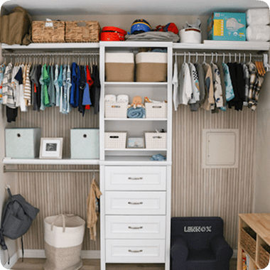 Organized closet with hanging clothes, storage boxes, and drawers.