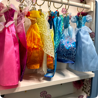 Colorful princess dresses hanging in a row on a rack.