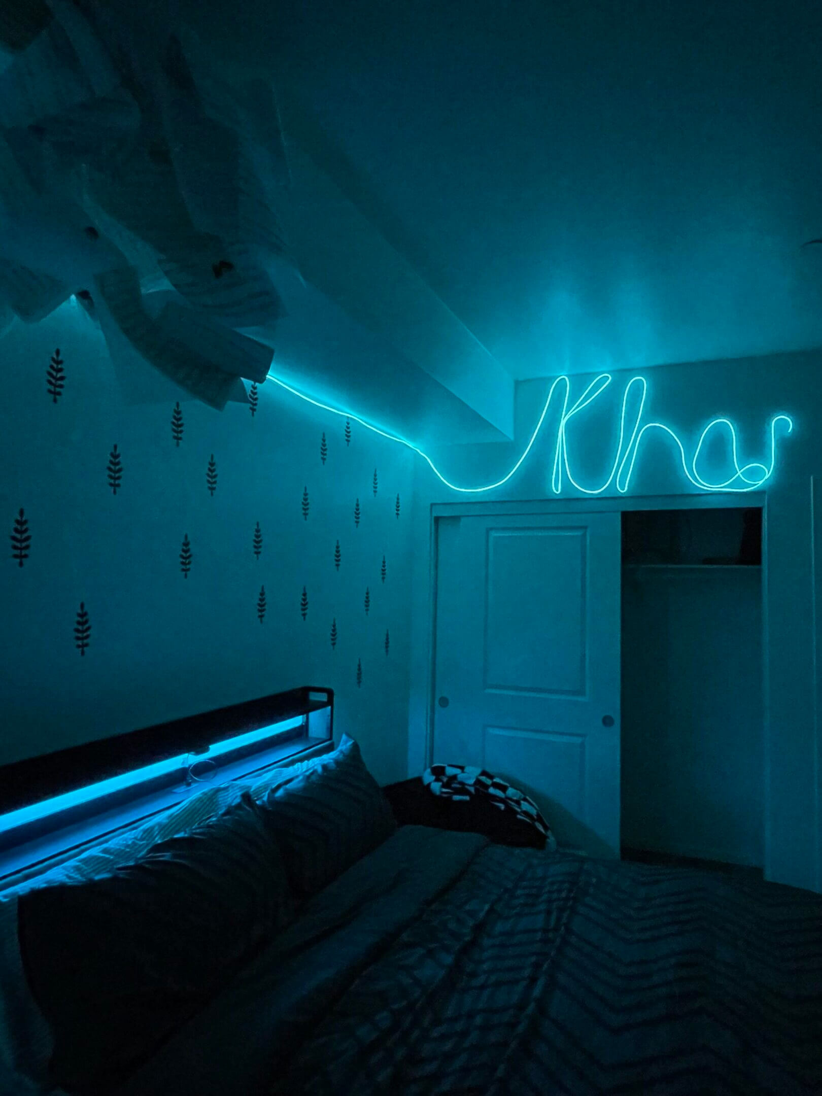 Cozy room with blue neon lights spelling 'Kha' and soft ambient lighting.