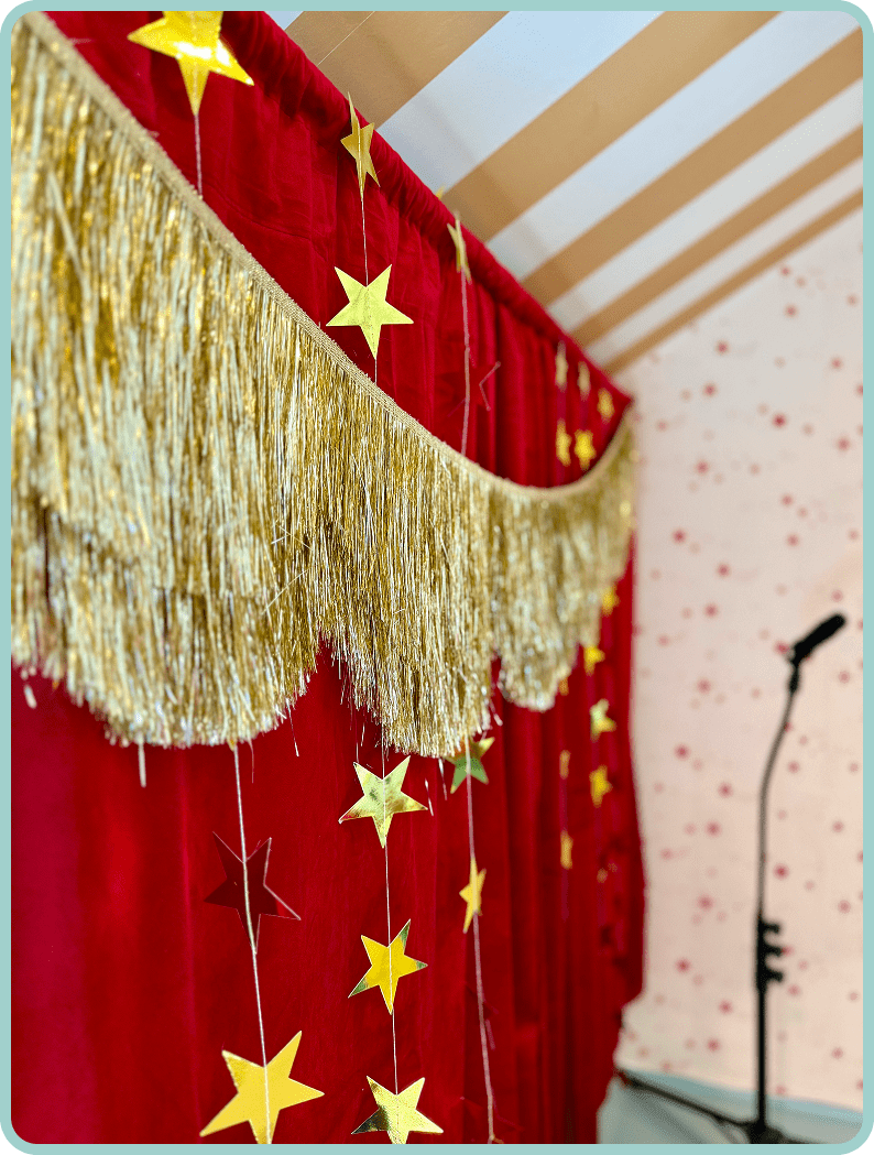Gold star decorations on red curtains with a microphone stand nearby.