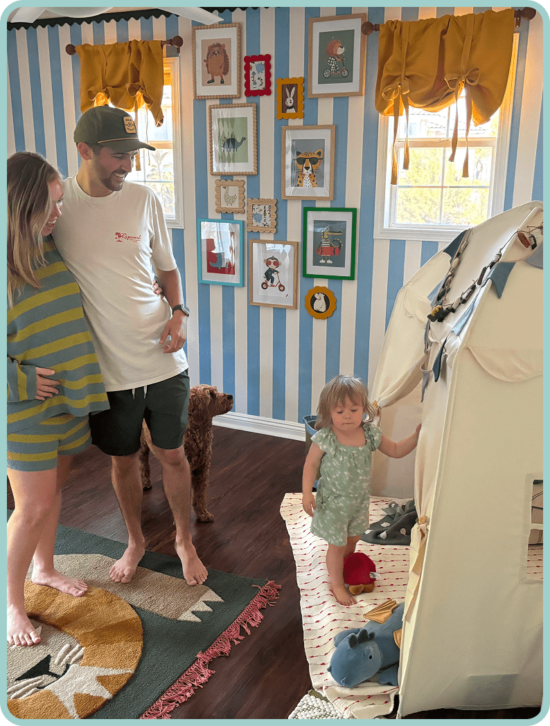 A child playing with a large toy and two adults watching.