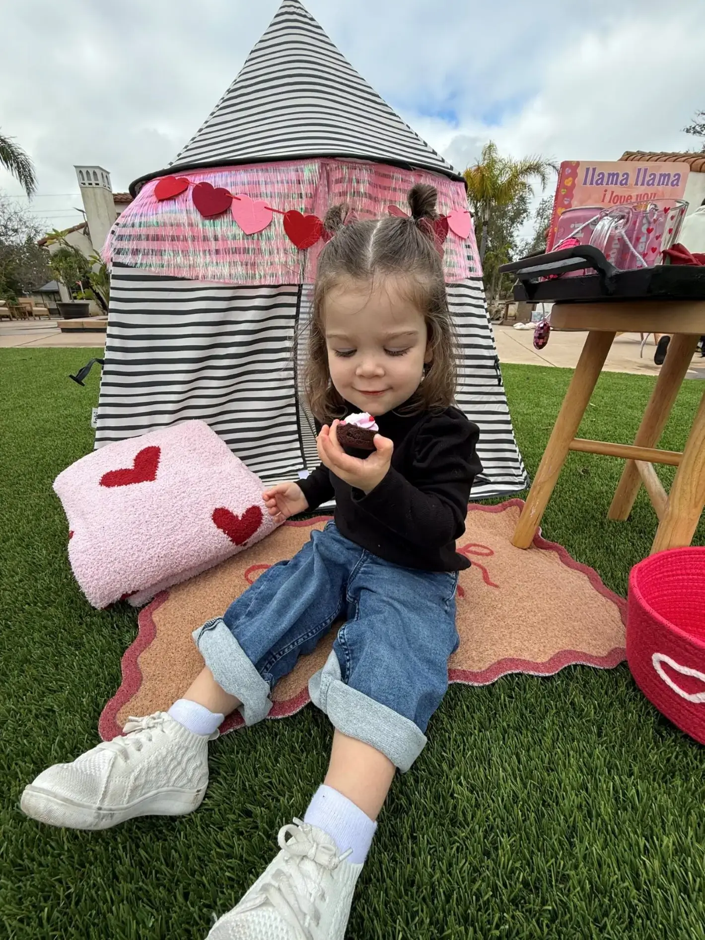 Little girl playing with a toy in a heart-decorated tent.